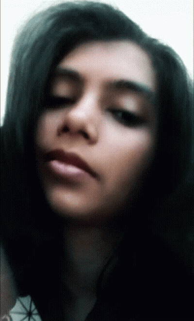 A Woman With Long Dark Hair Looks At The Camera GIF