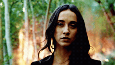 A Woman With Long Dark Hair Stands In Front Of A Forest Fire GIF