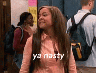 A Woman With Long Hair And A Backpack Is Standing In A Hallway With A Group Of People . GIF