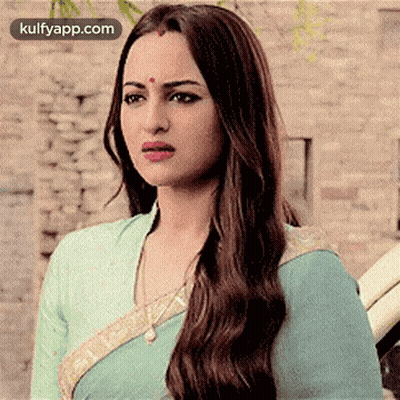 A Woman With Long Hair And A Bindi On Her Forehead Is Wearing A Blue Saree And Looking At The Camera . GIF
