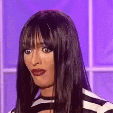 A Woman With Long Hair And Bangs Is Making A Funny Face . GIF