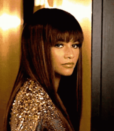 a woman with long hair and bangs is wearing a gold sequined dress .