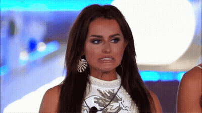 A Woman With Long Hair And Earrings Is Making A Funny Face While Standing In Front Of A Microphone . GIF