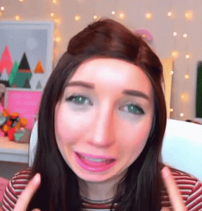 A Woman With Long Hair And Green Eyes Is Making A Funny Face GIF