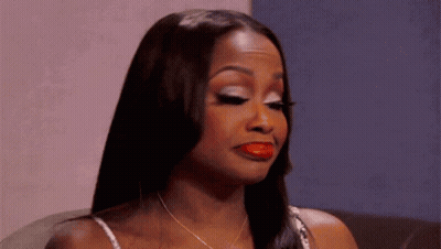 A Woman With Long Hair And Red Lipstick Is Sitting On A Couch . GIF