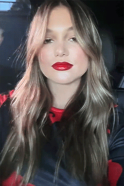A Woman With Long Hair And Red Lipstick Takes A Selfie In A Car GIF