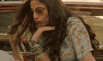 A Woman With Long Hair And Sunglasses Is Sitting In A Car . GIF