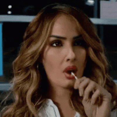 A Woman With Long Hair Is Eating A Lollipop . GIF