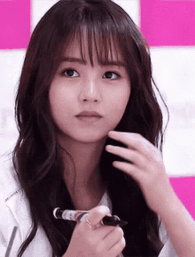 A Woman With Long Hair Is Holding A Marker In Her Hand And Looking At The Camera . GIF