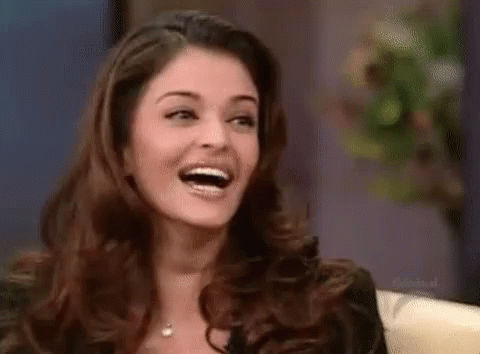 A Woman With Long Hair Is Laughing With Her Mouth Open . GIF