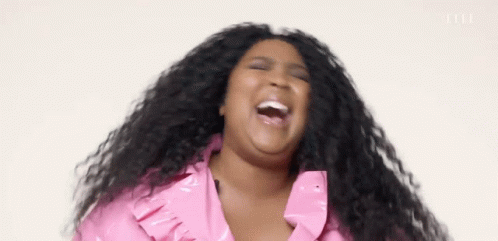 A Woman With Long Hair Is Laughing With Her Mouth Open And Wearing A Pink Jacket . GIF