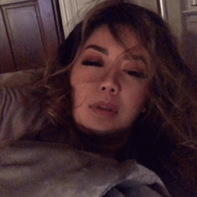 A Woman With Long Hair Is Laying Down With Her Mouth Open GIF