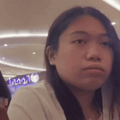 A Woman With Long Hair Is Making A Funny Face While Sitting In A Restaurant . GIF
