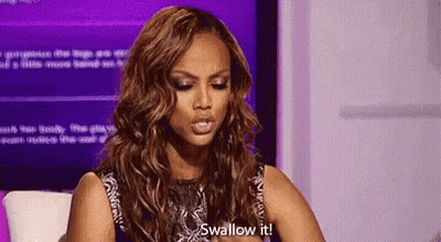 A Woman With Long Hair Is Sitting In Front Of A Purple Screen And Saying `` Swallow It '' . GIF