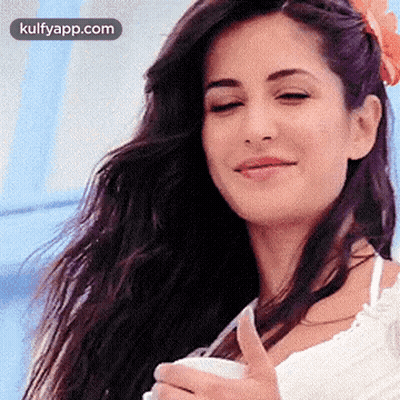 A Woman With Long Hair Is Smiling And Holding A Cup Of Coffee . GIF