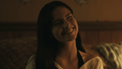 A Woman With Long Hair Is Smiling And Looking At The Camera GIF