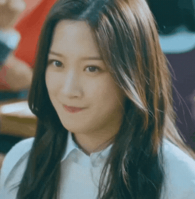 A Woman With Long Hair Is Smiling And Wearing A White Shirt GIF