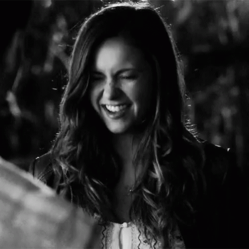 A Woman With Long Hair Is Smiling In A Black And White Photo . GIF