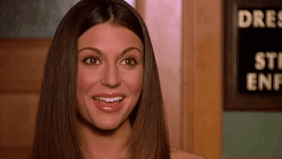 A Woman With Long Hair Is Smiling In Front Of A Sign That Says `` Steak Enf '' . GIF