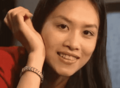 A Woman With Long Hair Is Smiling With Her Hand On Her Face . GIF