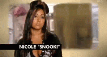 A Woman With Long Hair Is Standing In A Room With A Sign That Says Nicole Snooki . GIF