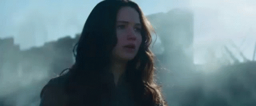 A Woman With Long Hair Is Standing In Front Of A Building In A Field . GIF
