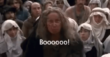 A Woman With Long Hair Is Standing In Front Of A Crowd Of People And Making A Funny Face . GIF