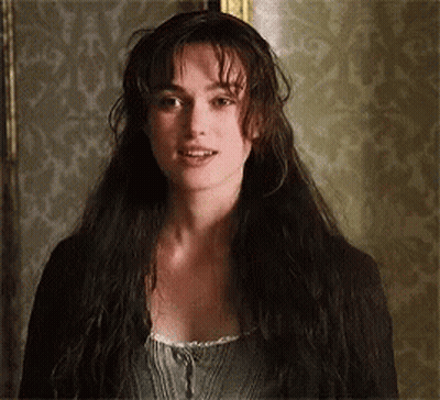 A Woman With Long Hair Is Standing In Front Of A Wall . GIF
