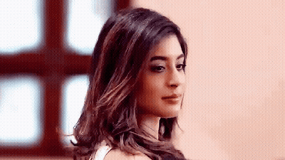 A Woman With Long Hair Is Standing In Front Of A Window Looking At The Camera . GIF