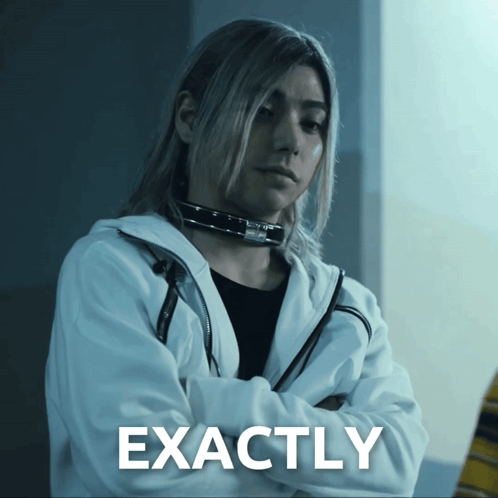 A Woman With Long Hair Is Standing With Her Arms Crossed In Front Of A Sign That Reads Exactly GIF