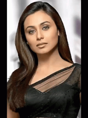 A Woman With Long Hair Is Wearing A Black Blouse And Looking At The Camera . GIF