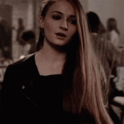 A Woman With Long Hair Is Wearing A Black Jacket And Earrings . GIF