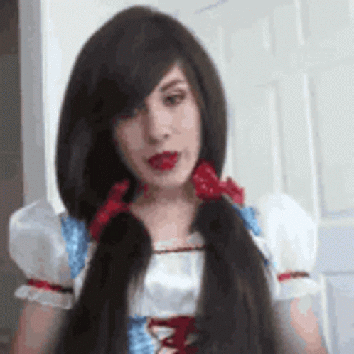 A Woman With Long Hair Is Wearing A Snow White Costume And Has A Red Bow In Her Hair . GIF