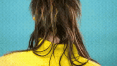 A Woman With Long Hair Is Wearing A Yellow Jacket And A Yellow Shirt . GIF