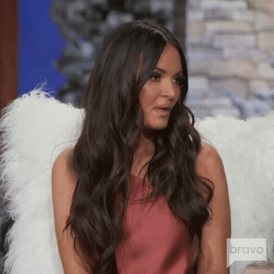 A Woman With Long Hair Is Wearing Angel Wings And A Bravo Logo GIF