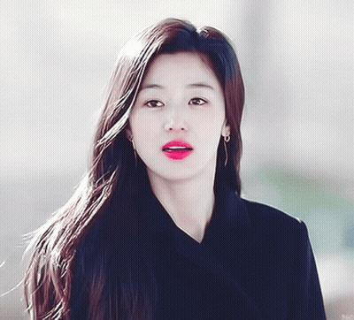 A Woman With Long Hair Is Wearing Earrings And A Black Coat GIF