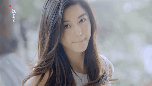 A Woman With Long Hair Looks At The Camera With A Foreign Language Written On The Bottom Right Corner GIF