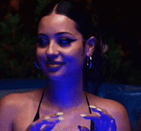 A Woman With Long Nails Is Sitting In A Dark Room With Blue Lights . GIF