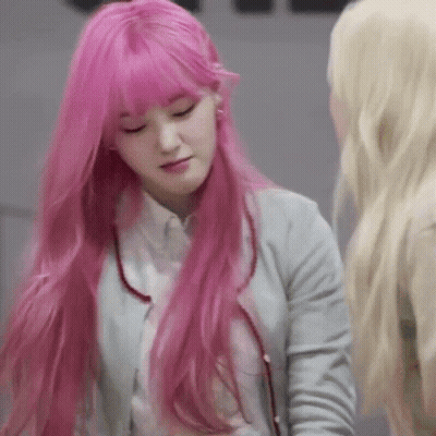 A Woman With Long Pink Hair And Bangs Is Standing Next To Another Woman . GIF