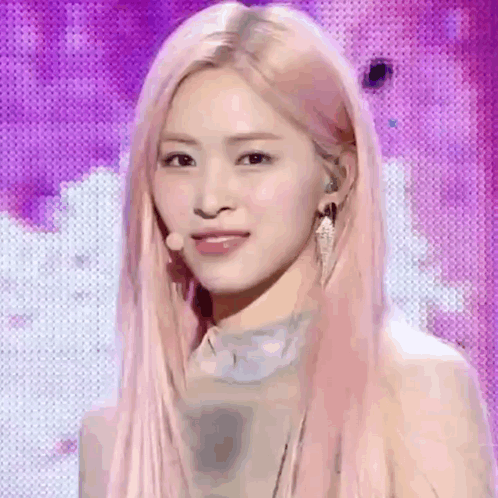 A Woman With Long Pink Hair Is Standing In Front Of A Purple Background . GIF