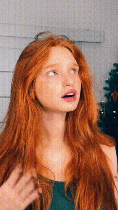 A Woman With Long Red Hair And Blue Eyes Looks Up At Something GIF