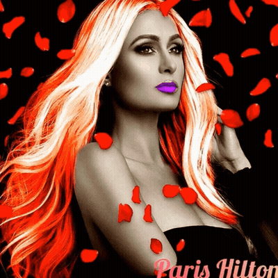 A Woman With Long Red Hair And Purple Lips Is Surrounded By Red Rose Petals And The Name Paris Hilton GIF