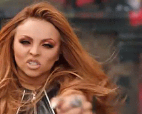 A Woman With Long Red Hair Is Making A Funny Face And Pointing At The Camera . GIF