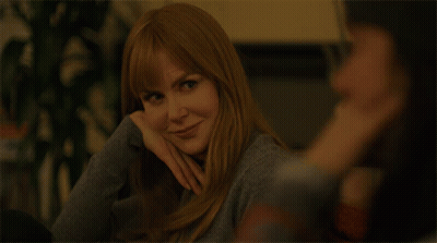 A Woman With Long Red Hair Is Smiling And Looking At The Camera GIF
