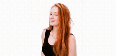 A Woman With Long Red Hair Is Smiling And Wearing A Black Tank Top . GIF