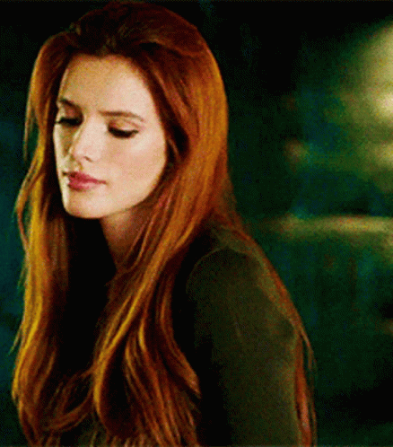 A Woman With Long Red Hair Is Wearing A Black Shirt And Looking Down . GIF