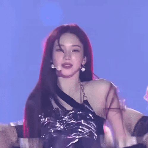 A Woman With Long Red Hair Is Wearing A Black Top And Silver Skirt GIF