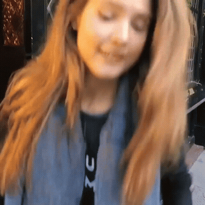 A Woman With Long Red Hair Is Wearing A Jacket With The Letter X On It GIF
