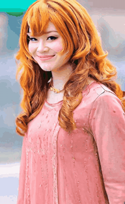 A Woman With Long Red Hair Is Wearing A Pink Top GIF