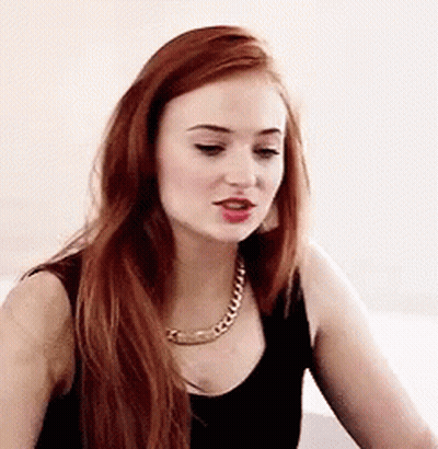A Woman With Long Red Hair Wearing A Black Tank Top And A Gold Chain Necklace . GIF